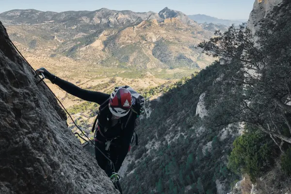 Persona subiendo por las paredes de la Vía ferrata Norte del Cid en su parte inicial.